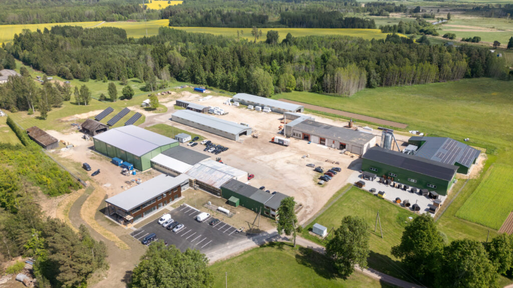 Capra Saunas manufacturing complex with production buildings, storage areas, solar panels, parking facilities, and surrounding countryside.